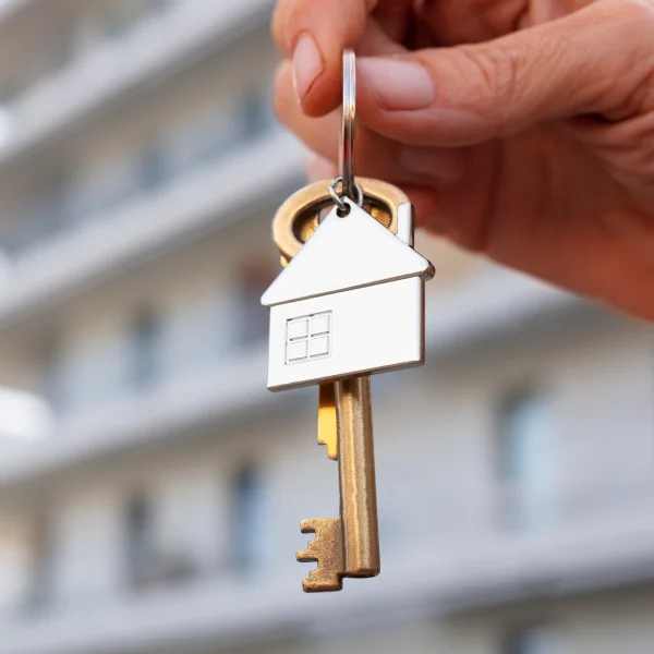 Une personne tenant une clé avec une maison dessus. Symbolise un contrat de vente immobilier.