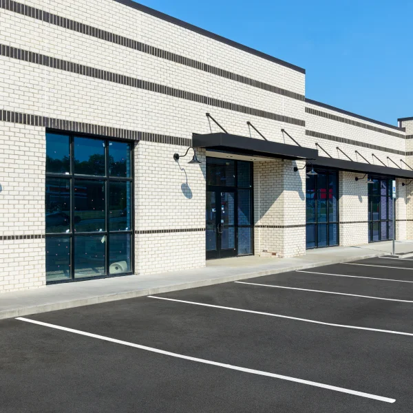 Un parking avec un immeuble commercial à vendre en arrière-plan.