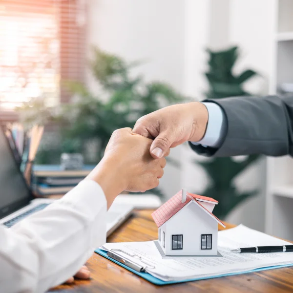 Trois personnes assises à une table examinant un document lié au courtage immobilier.