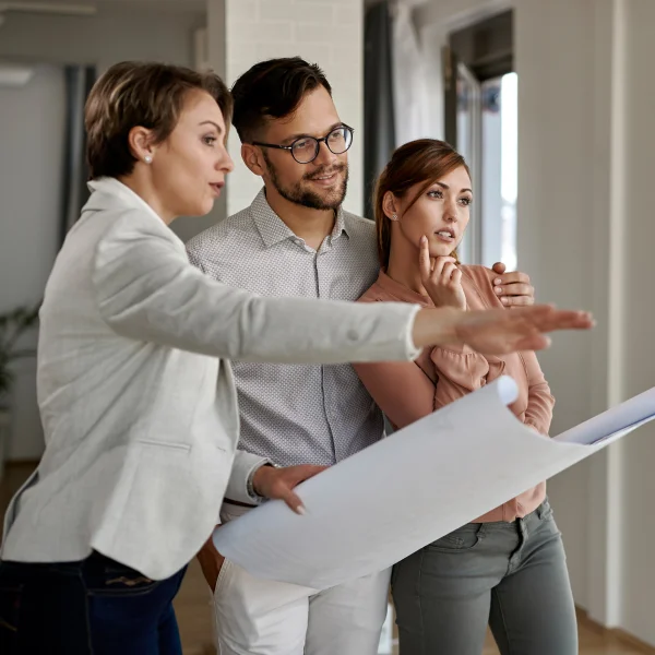Trois personnes debout dans un bureau avec un plan.