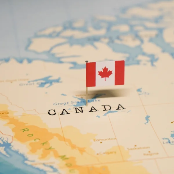 Drapeau du Canada superposé sur une carte du monde, symbolisant l'immobilier au Canada. Meilleur courtier immobilier.