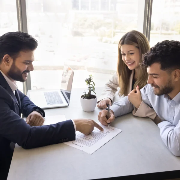 Un homme et une femme se serrent la main au-dessus d'un modèle de maison, symbolisant une transaction de courtage immobilier.