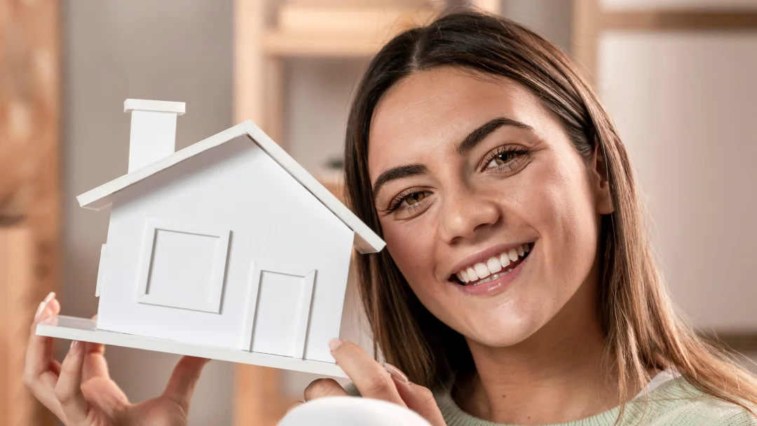 Une femme tenant un modèle de maison.